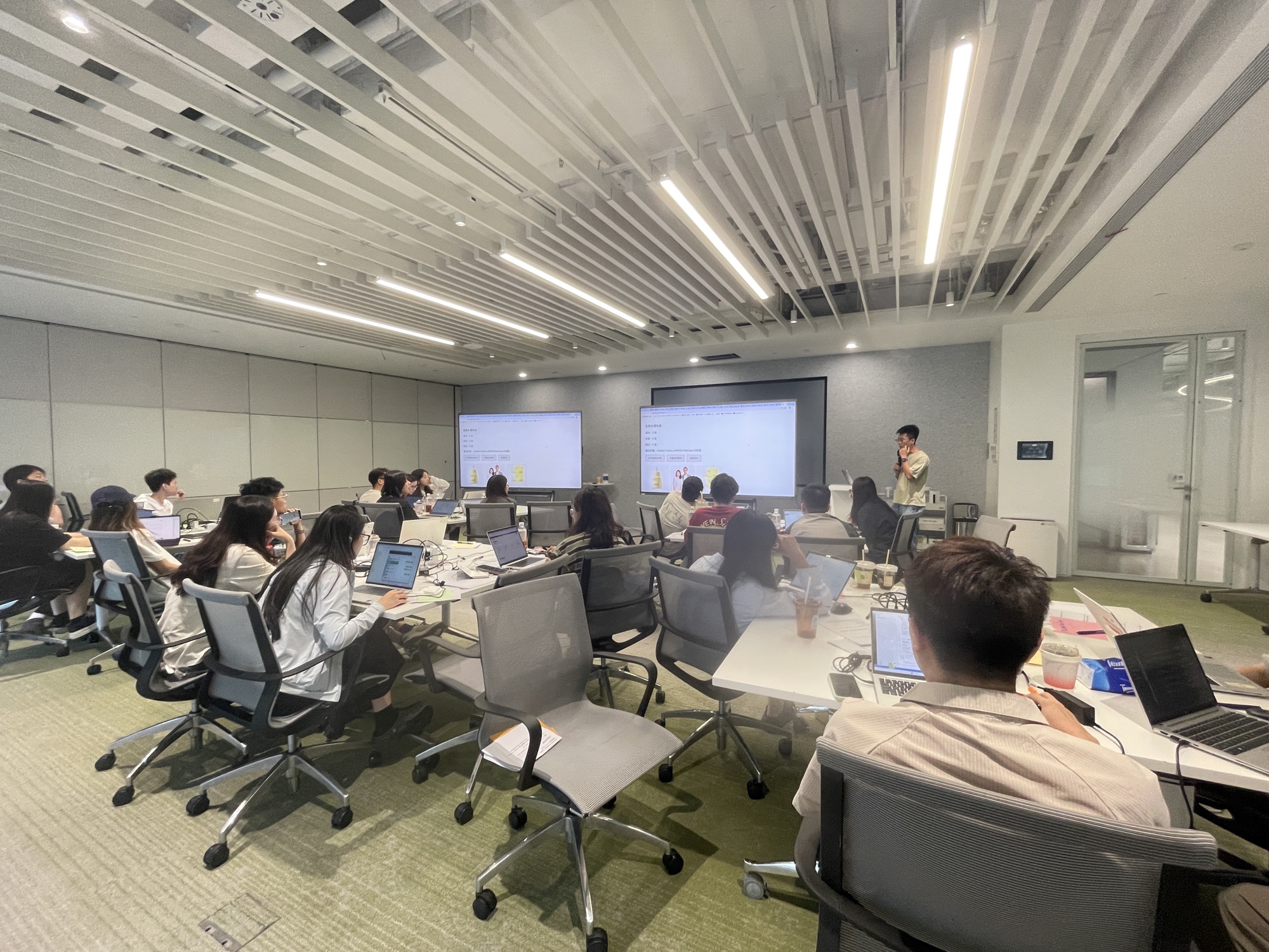 AI Coding 工作坊现场,学员观看讲师与同伴展示业务工具成果