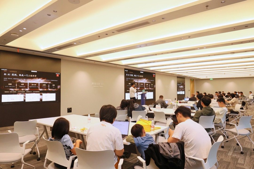 会场内参赛团队三三两两坐在长桌前用笔记本开发,房间后方是一整排智能屏幕