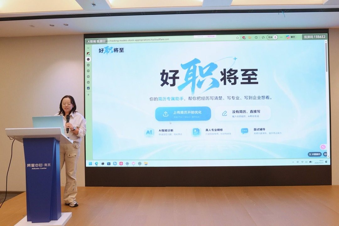 参赛者在阿里中心的讲台上路演,大屏展示作品「好职将至」的产品界面