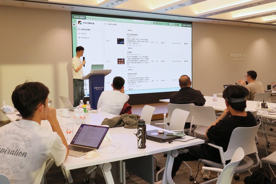 路演现场,讲者在大屏前讲解作品功能,台下参与者围坐交流