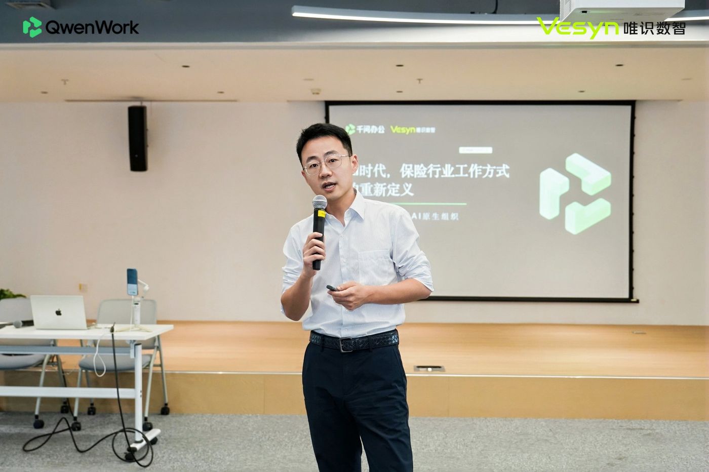 第一位分享嘉宾在台上讲解「AI 时代,保险行业工作方式的重新定义」,身后大屏展示相关主题